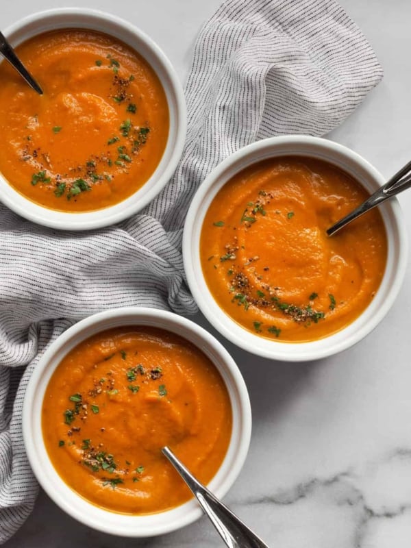 Three bowls of roasted carrot soup.