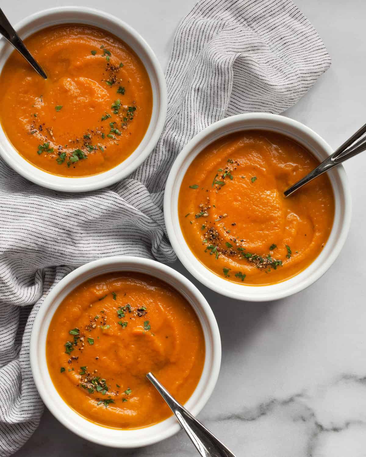 Three bowls of roasted carrot soup.