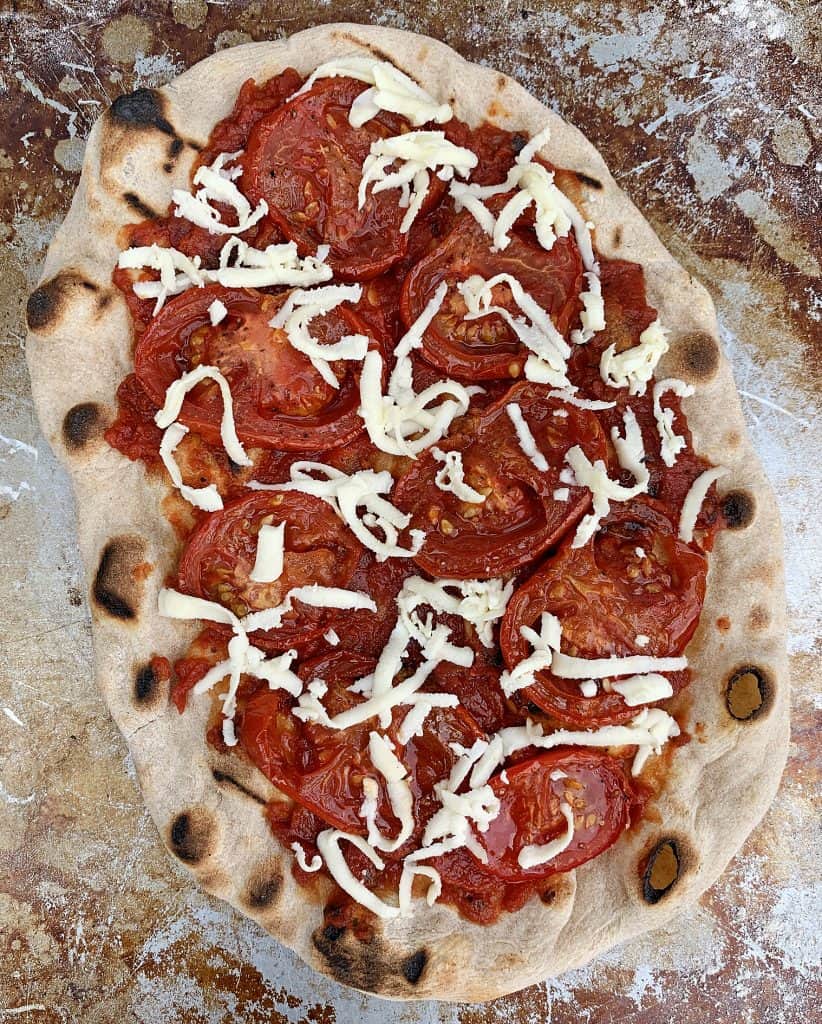 Putting toppings on the grilled pizza crust