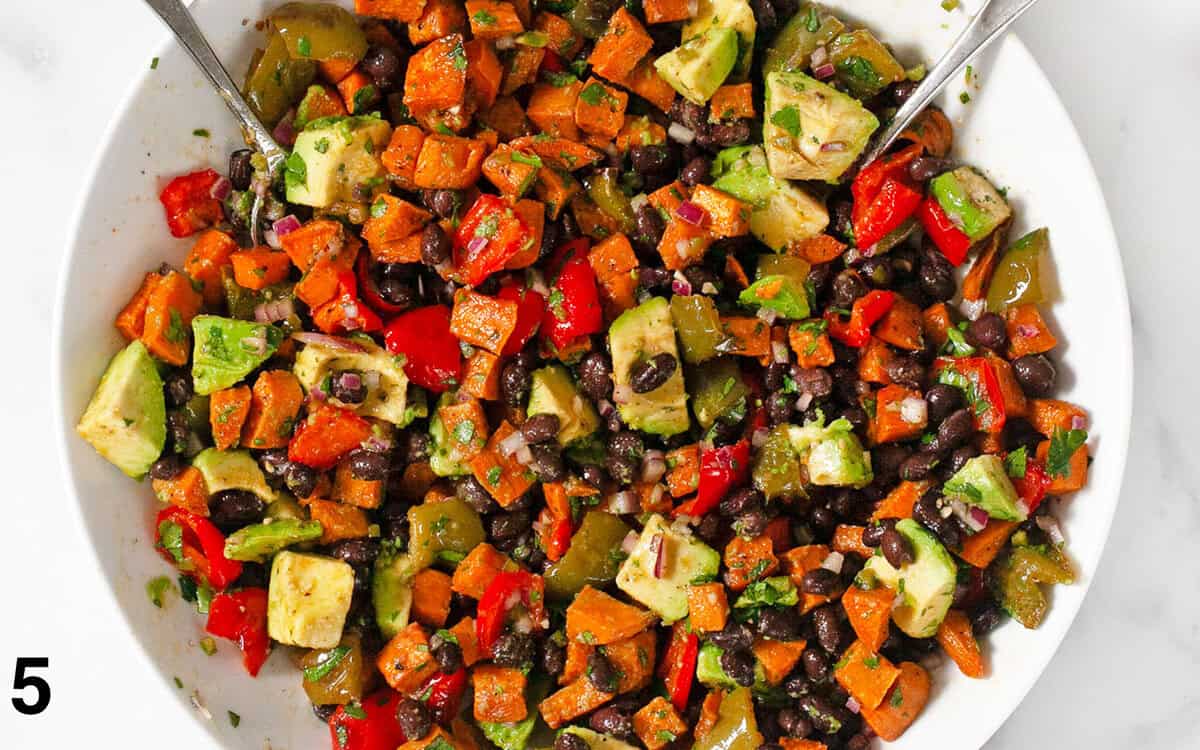 Salad ingredients tossed with dressing in a large bowl.