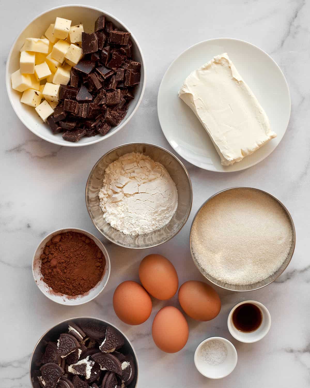 Ingredients including chocolate, cocoa powder, sugar, flour, butter, cream cheese, eggs and salt.