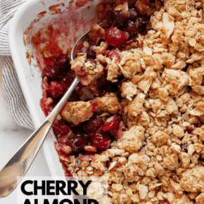 Cherry crumble in a baking dish with a spoon.
