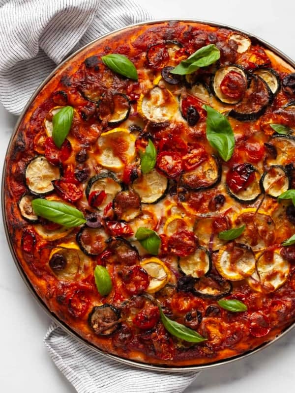 Roasted vegetable pizza topped with fresh basil.