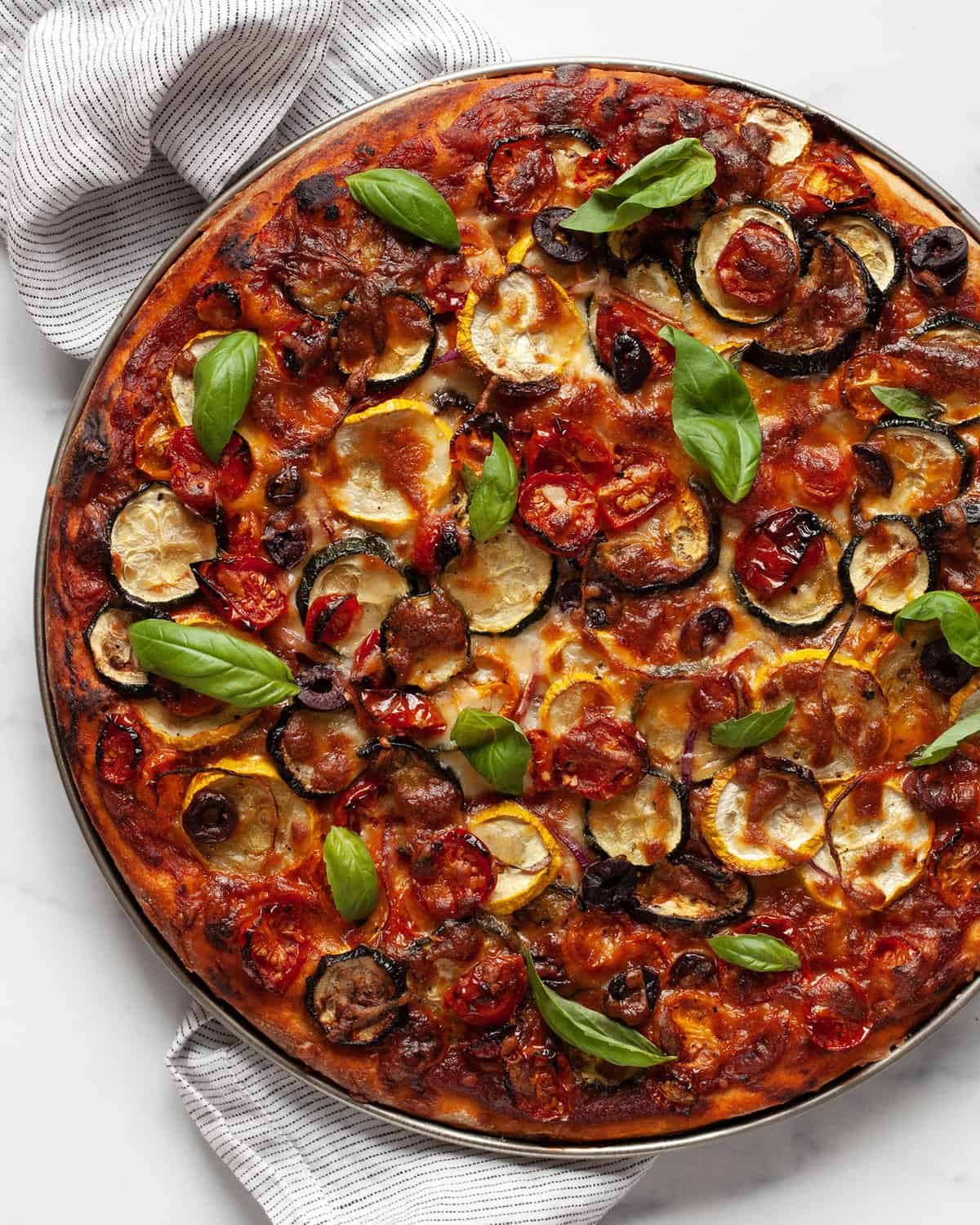 Roasted vegetable pizza topped with fresh basil.