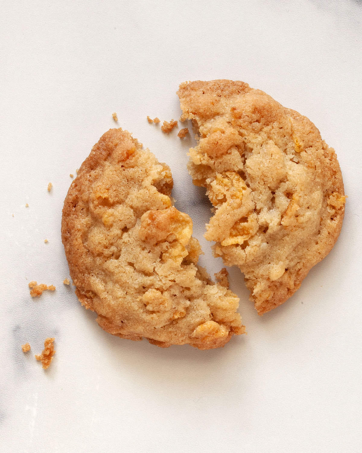 One cornflake cookie broken in half.