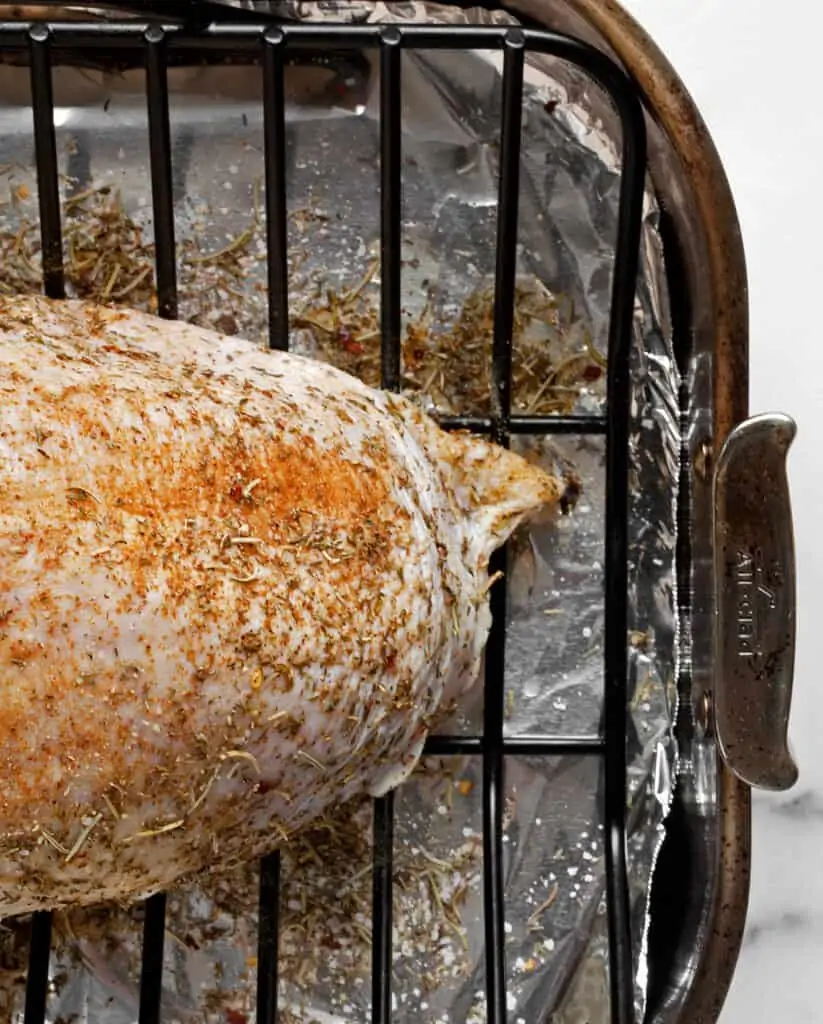 Bone-in turkey breast rubbed with dry seasoning mix on a rack in a roasting pan
