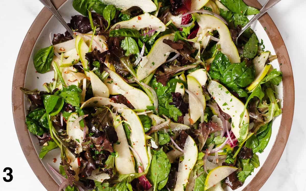 Salad ingredients tossed with dressing in a large bowl.