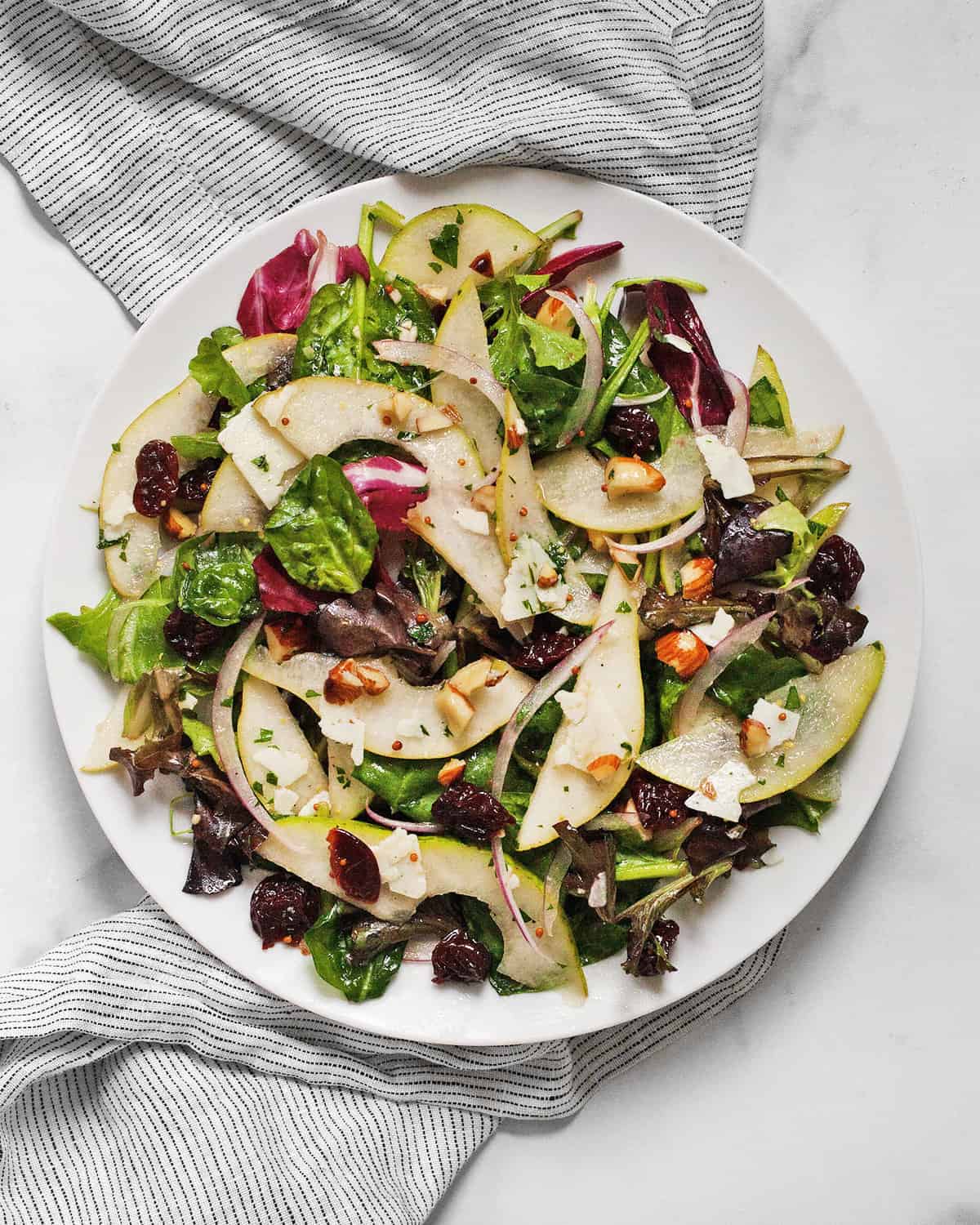 Pear mixed greens salad on a plate.