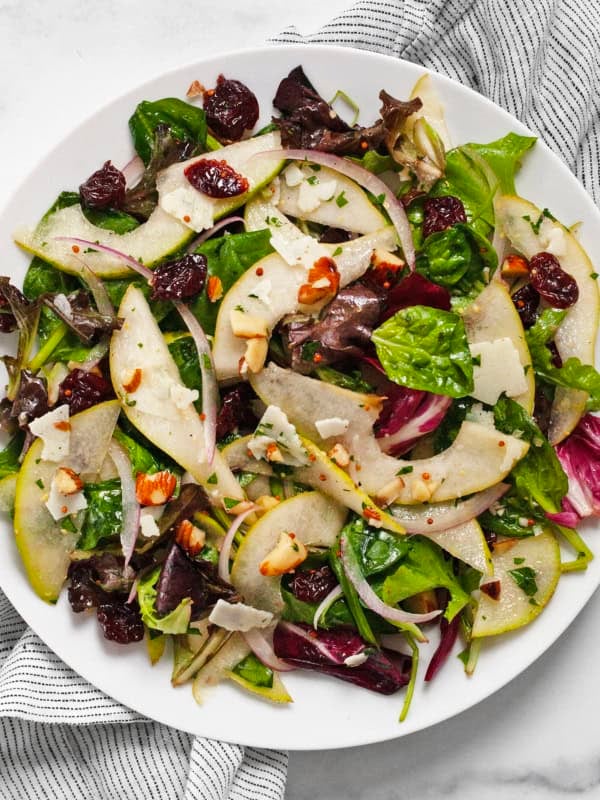 Pear mixed greens salad on a plate.