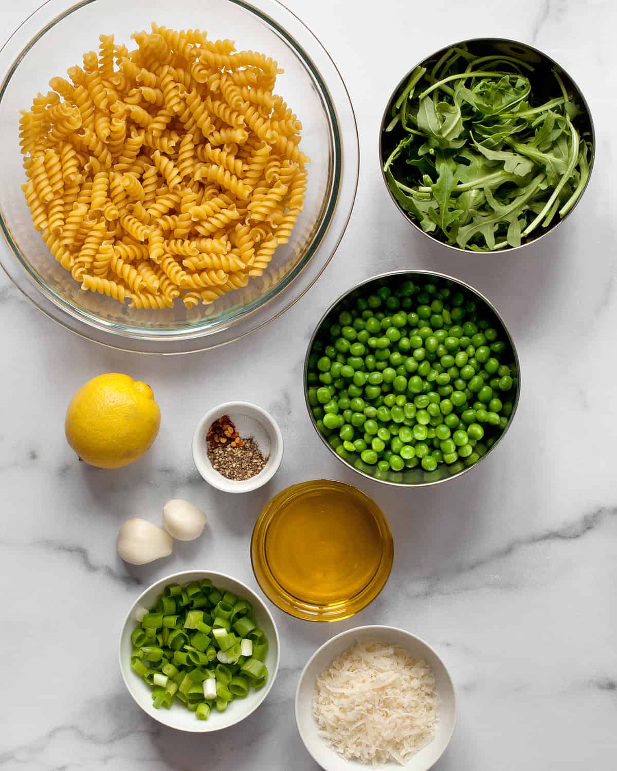 Ingredients including pasta, peas, lemon, arugula, garlic, olive oil and spices