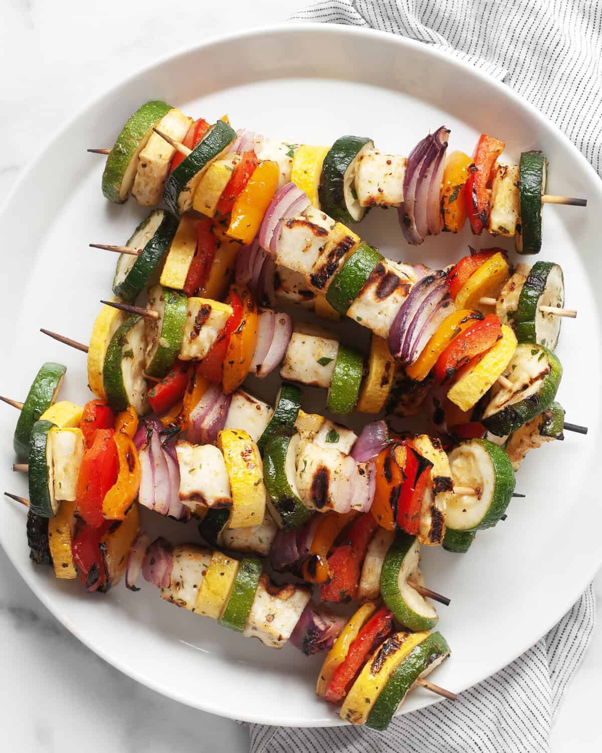 Grilled halloumi veggie skewers on a plate.