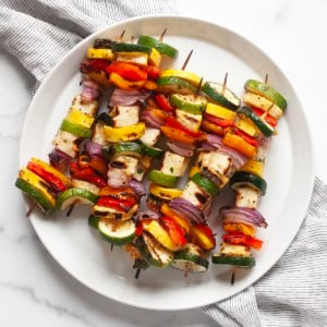 Grilled halloumi veggie skewers on a plate.