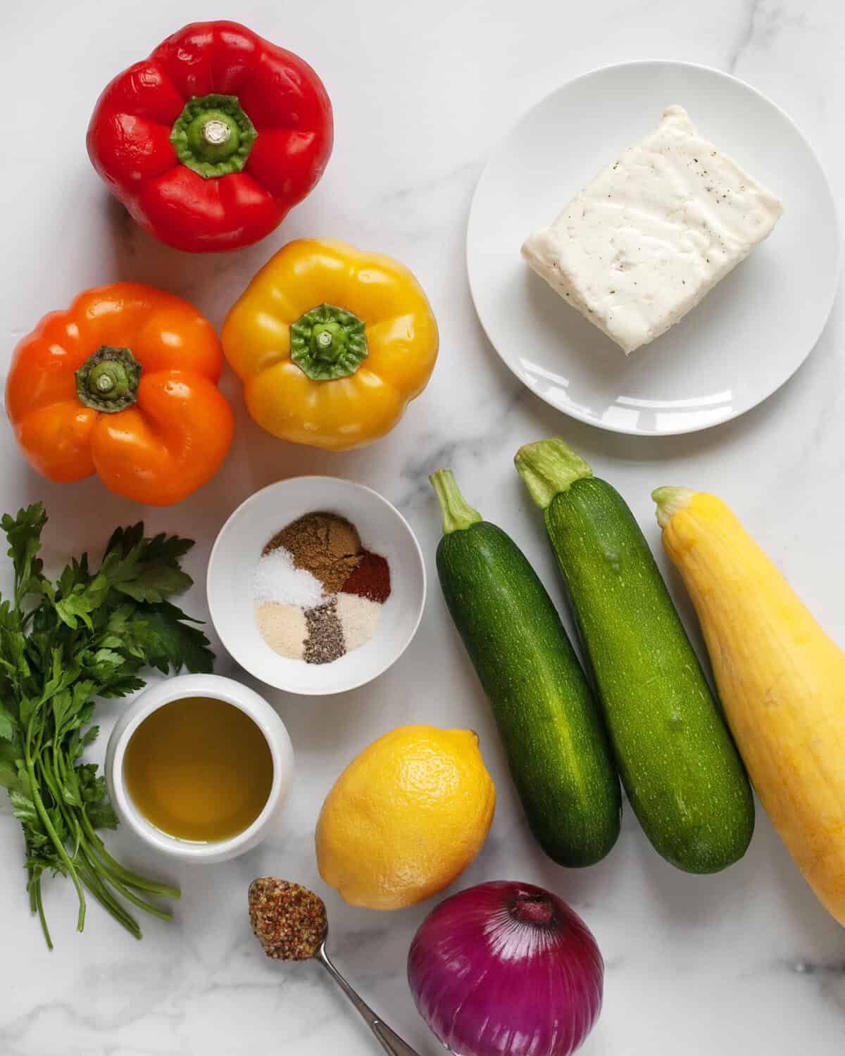 Ingredients including halloumi, bell peppers, zucchini, yellow squash, red onion, lemon, parsley, olive oil, mustard and seasonings.