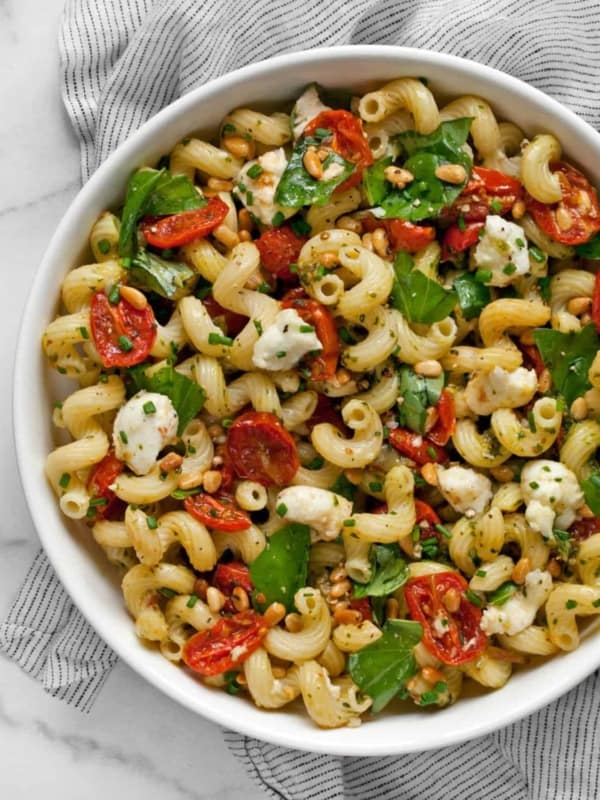 Pesto pasta salad with roasted tomatoes and mozzarella in a bowl.