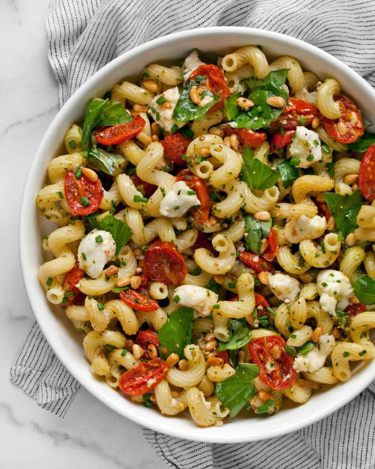 Pesto pasta salad with roasted tomatoes and mozzarella in a bowl.