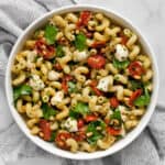 Pesto pasta salad with roasted tomatoes and mozzarella in a bowl.