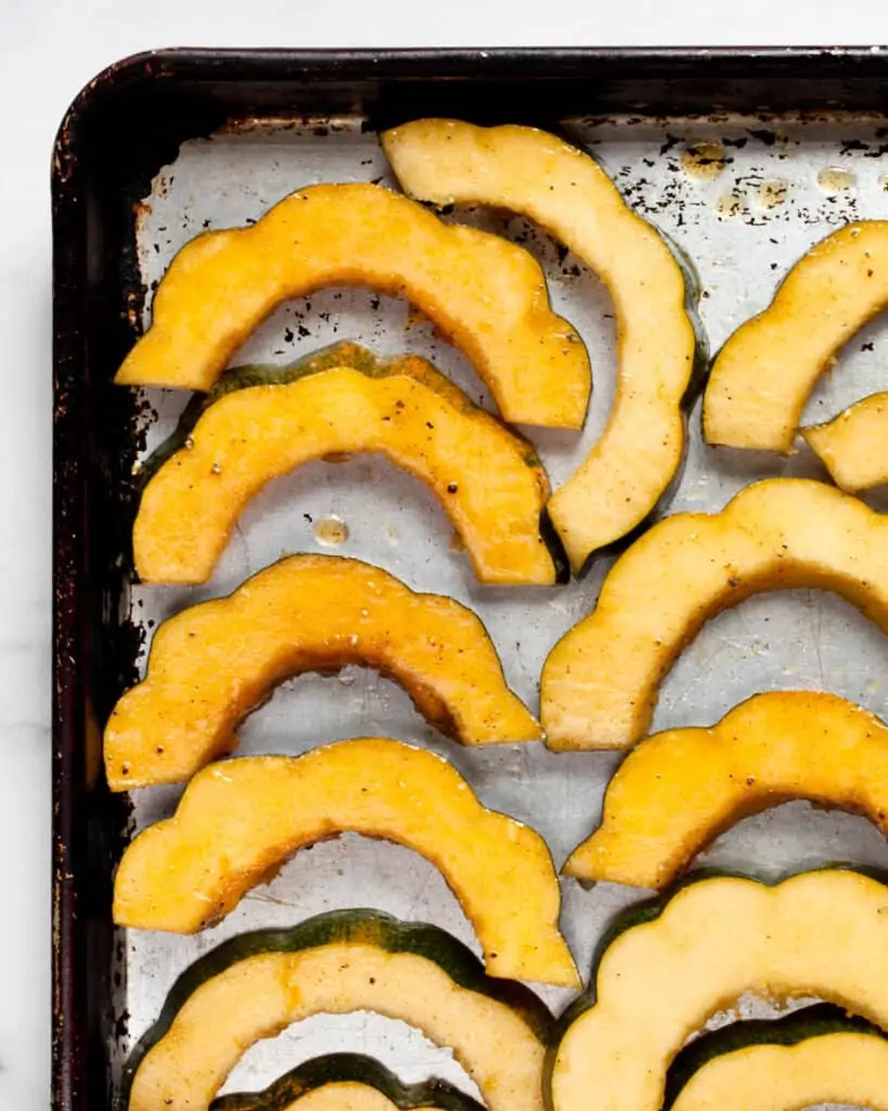 Acorn squash slices on a baking sheet
