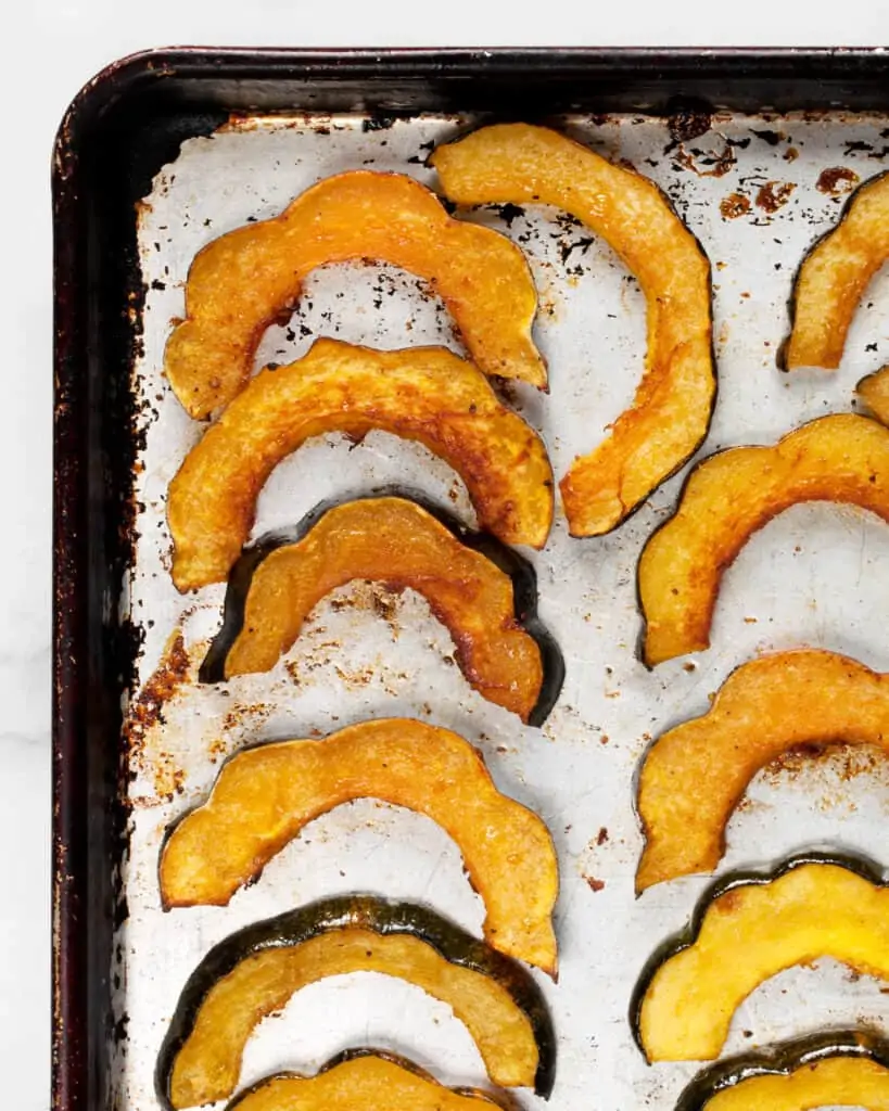Roasted acorn squash slices on a baking sheet