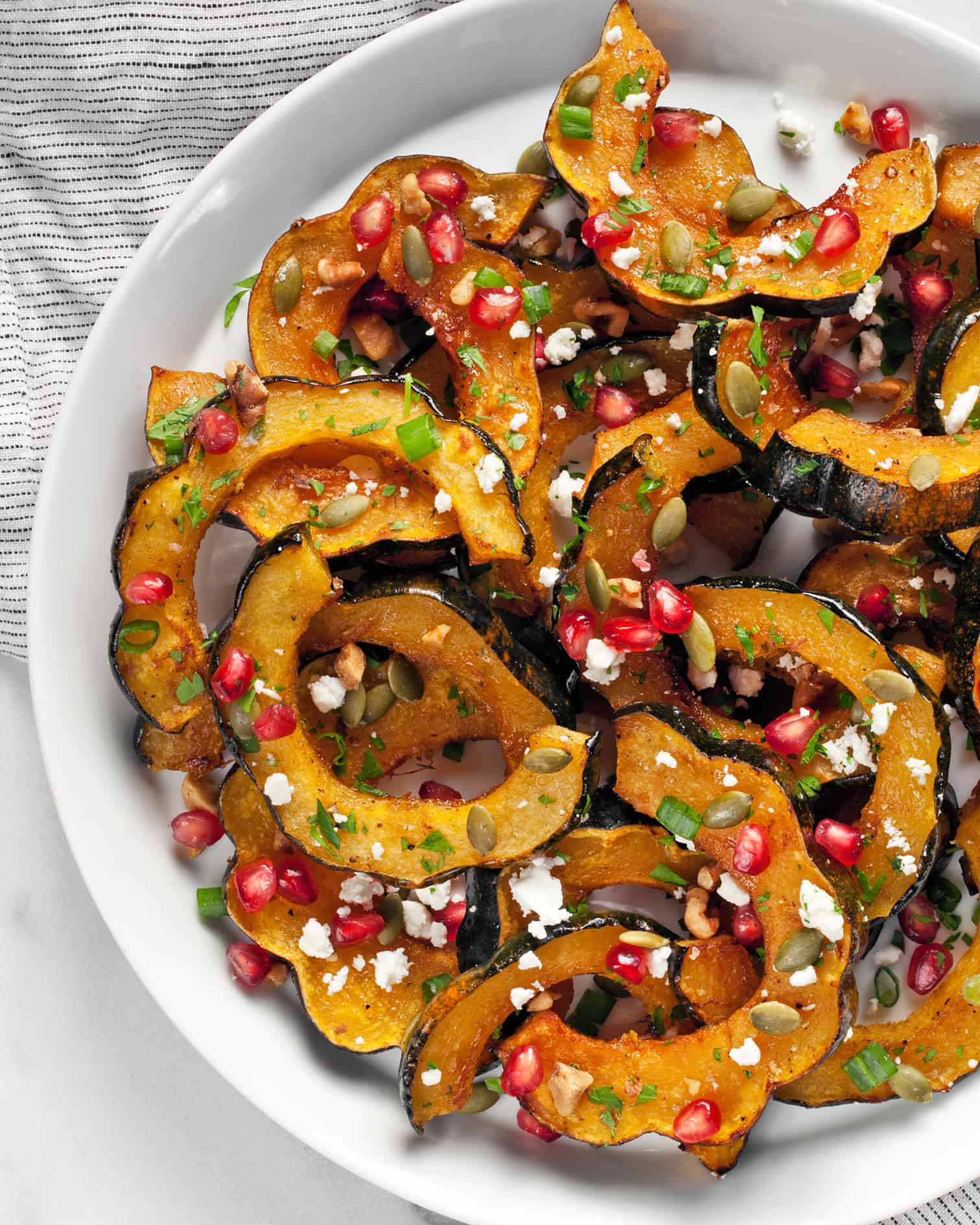 Roasted acorn squash slices arranges on a plate.