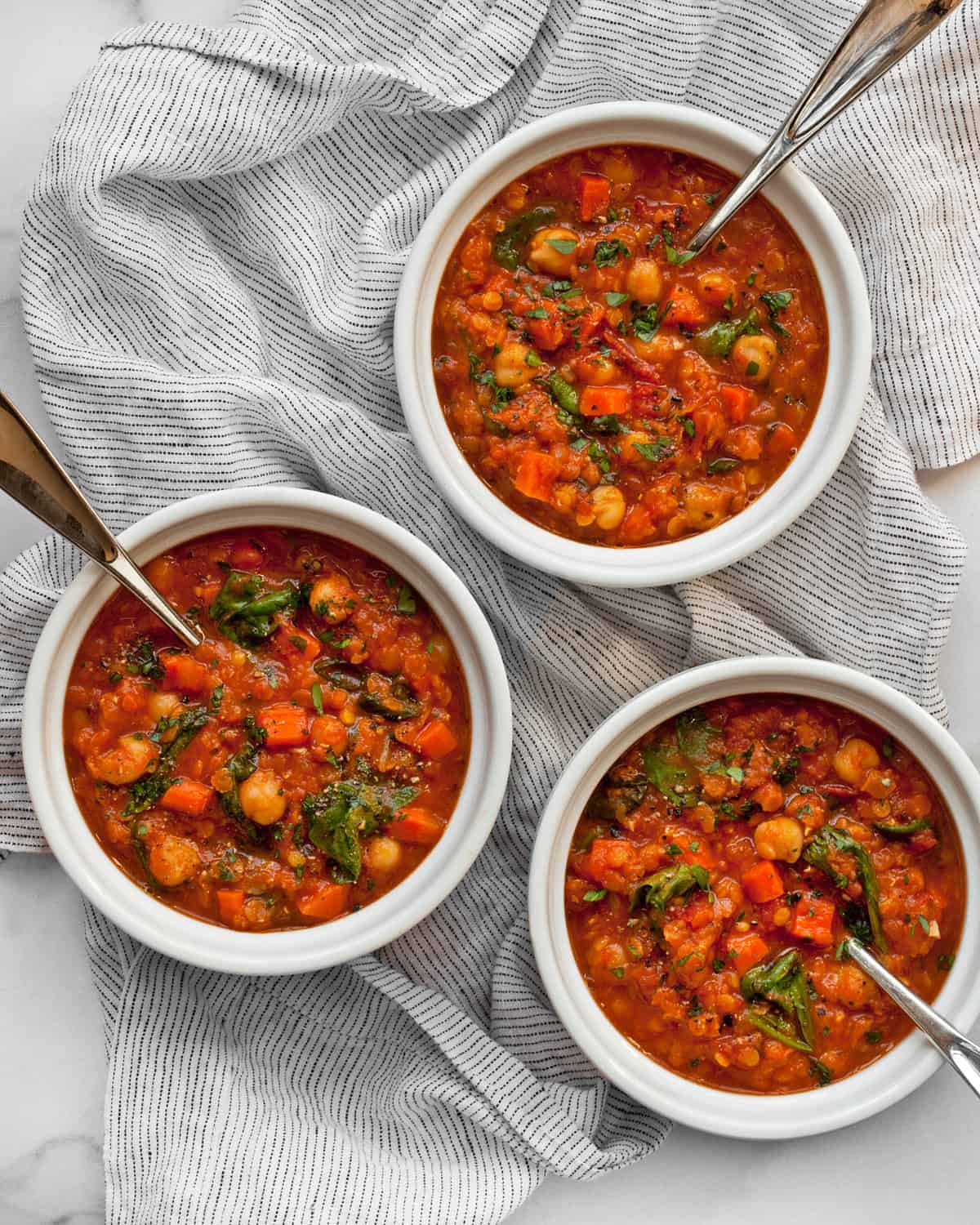 Three bowls of red lentil soup.