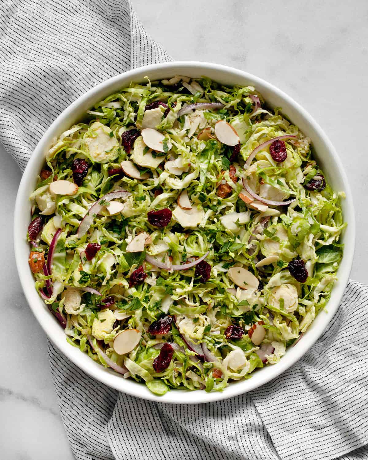 Brussels sprout salad with almonds, cranberries and parmesan in a bowl.