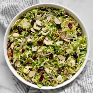 Shaved brussels sprout salad with cranberries. almonds and parmesan in a large bowl.