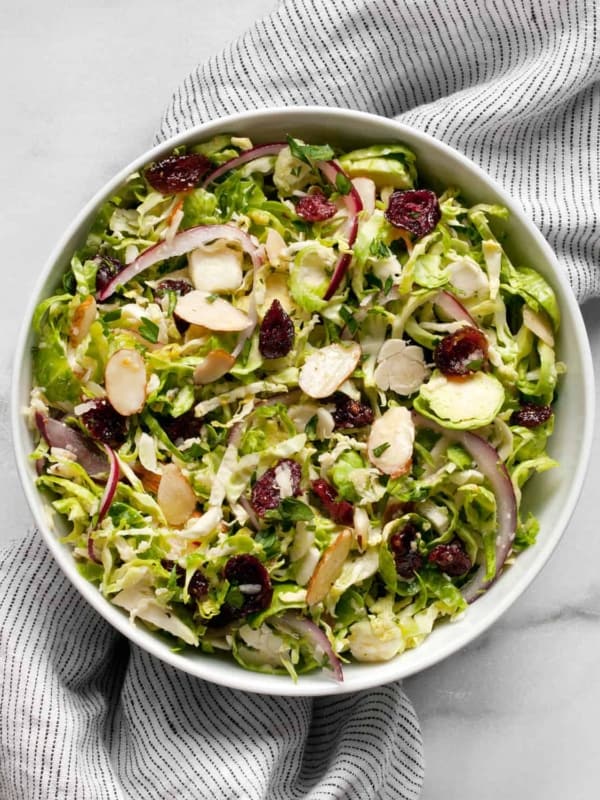 Shredded brussels sprout salad with cranberries. almonds and parmesan in a small bowl.