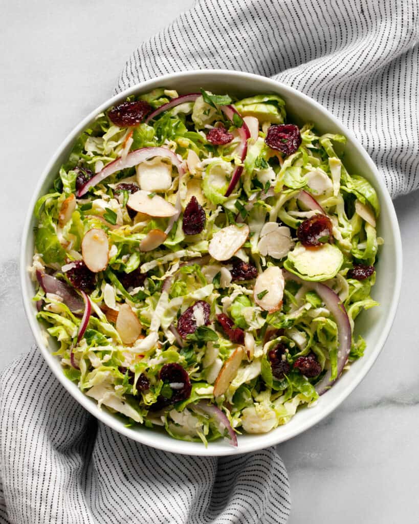 Shredded brussels sprout salad with cranberries. almonds and parmesan in a small bowl.