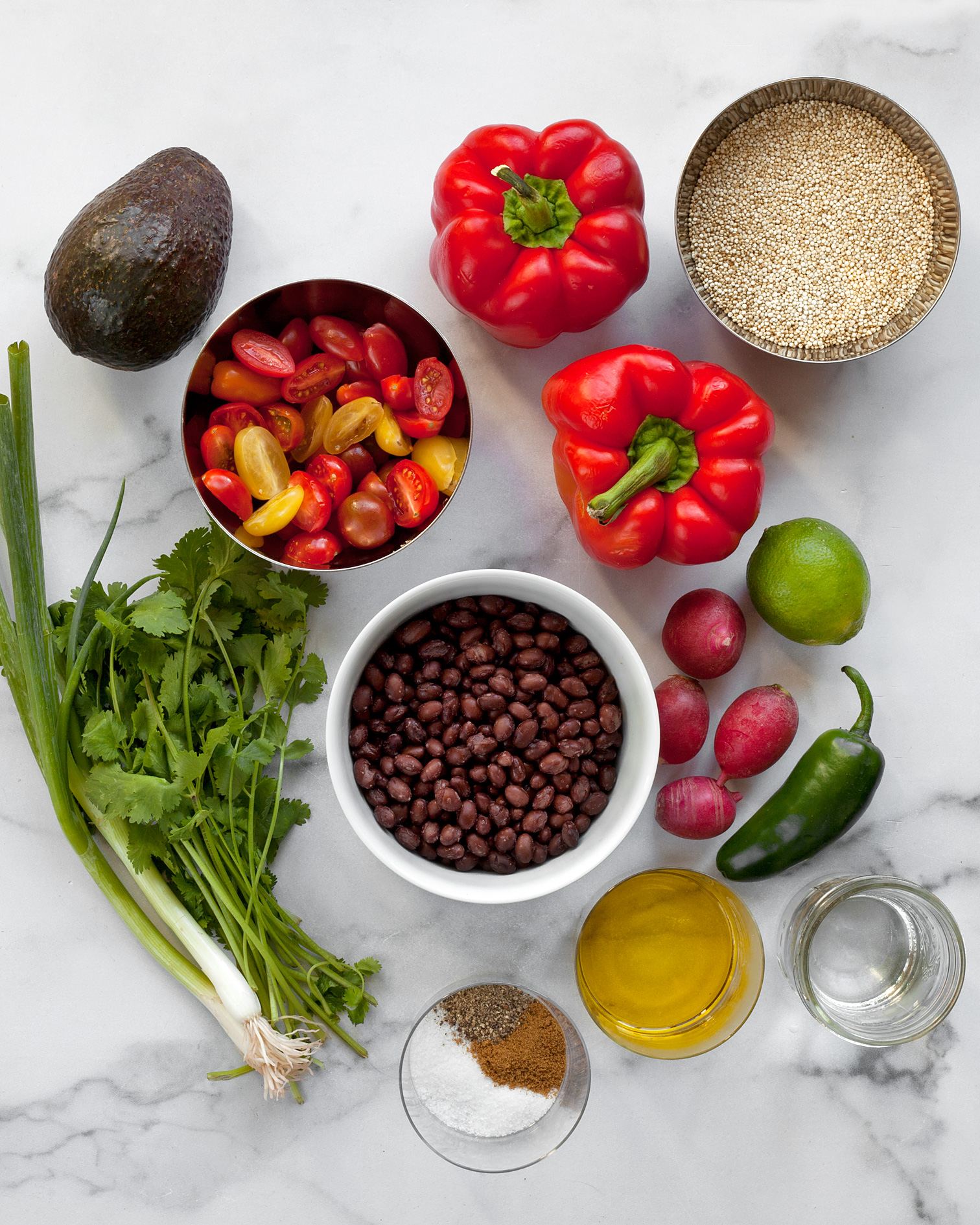 Ingredients including quinoa, black beans, peppers, tomatoes, avocado, cilantro and scallions.