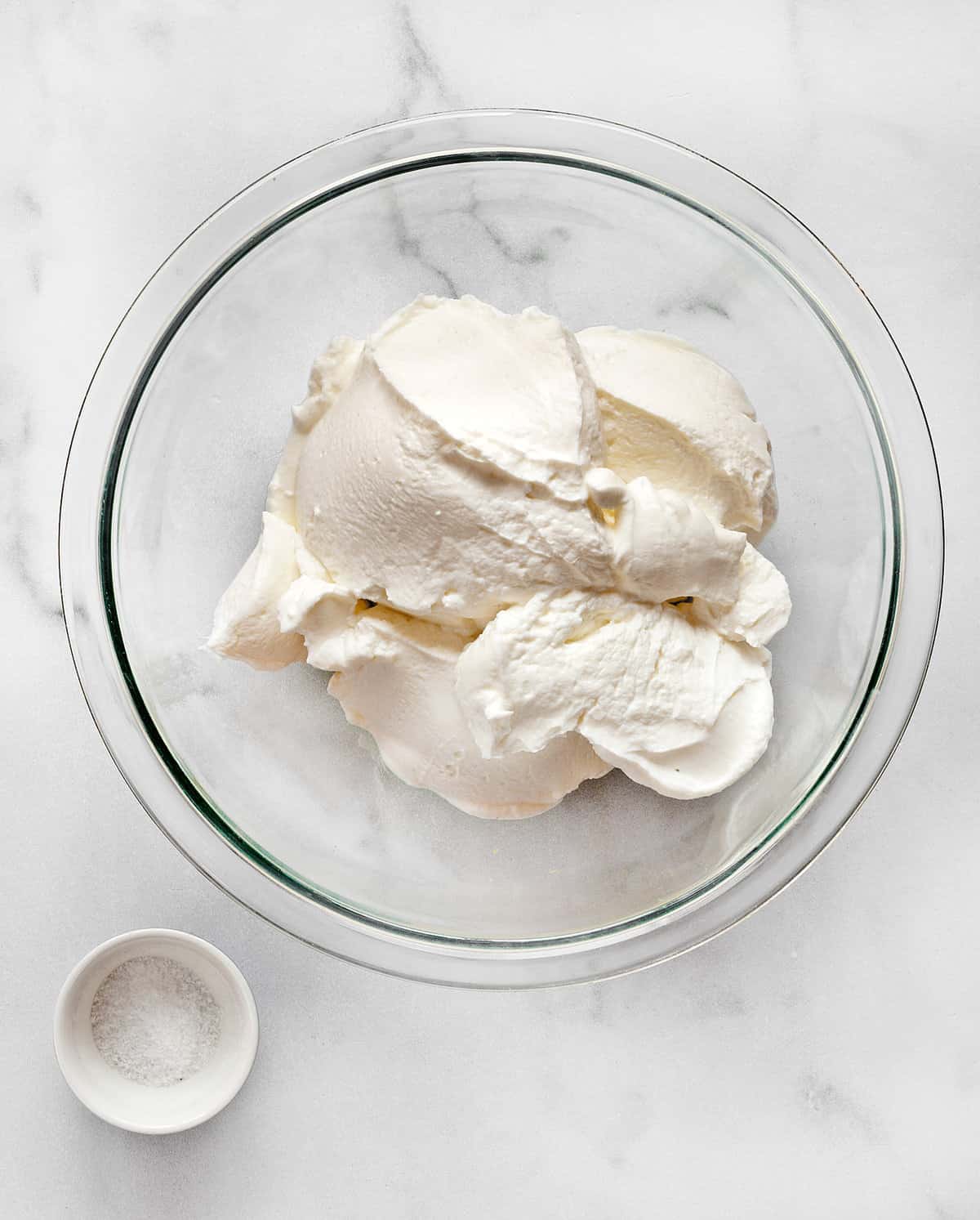 Greek yogurt in a large bowl with small container of salt.