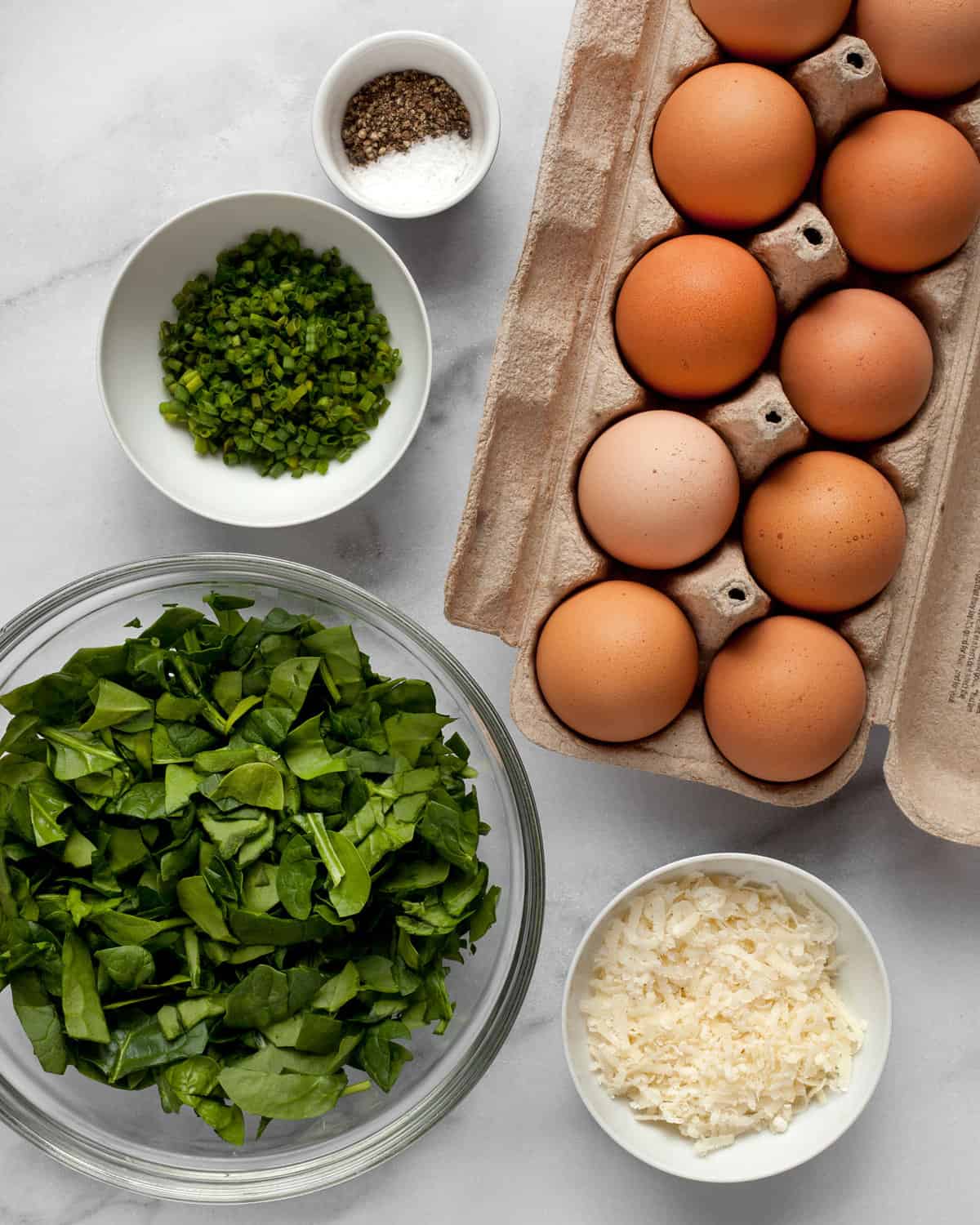 Ingredients for frittatas including eggs, spinach, parmesan, chives, salt and pepper.