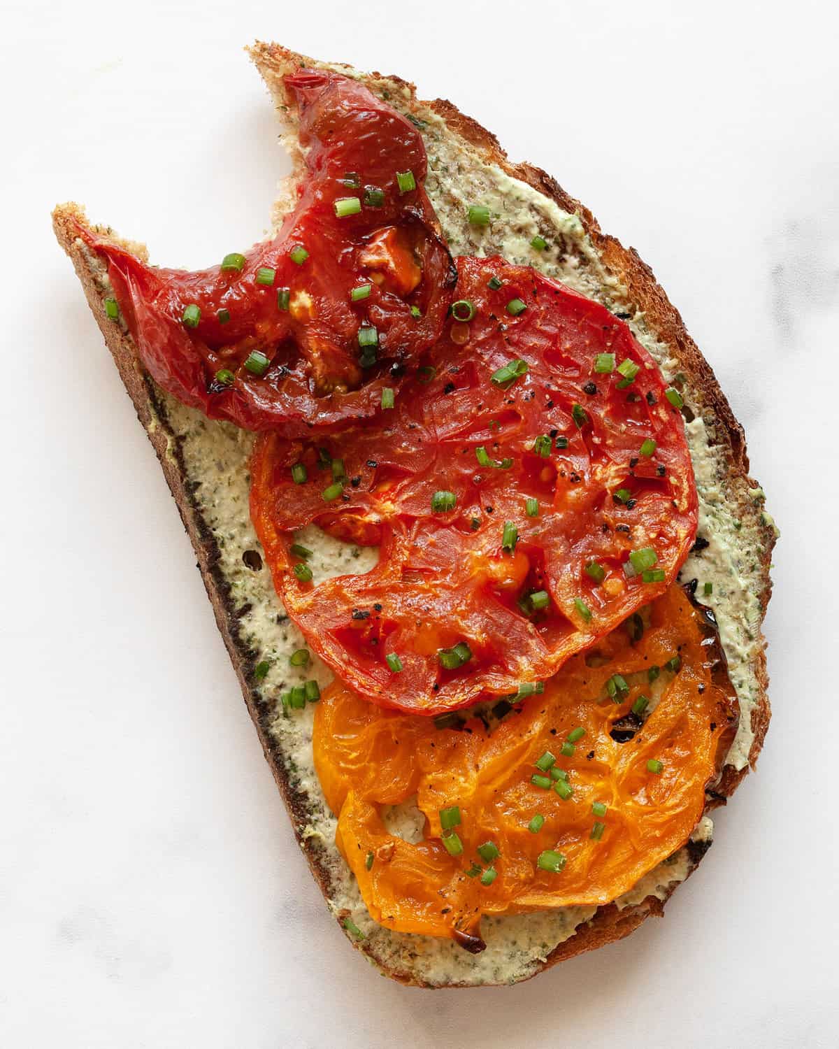 One slice of tomato toast with a bite.