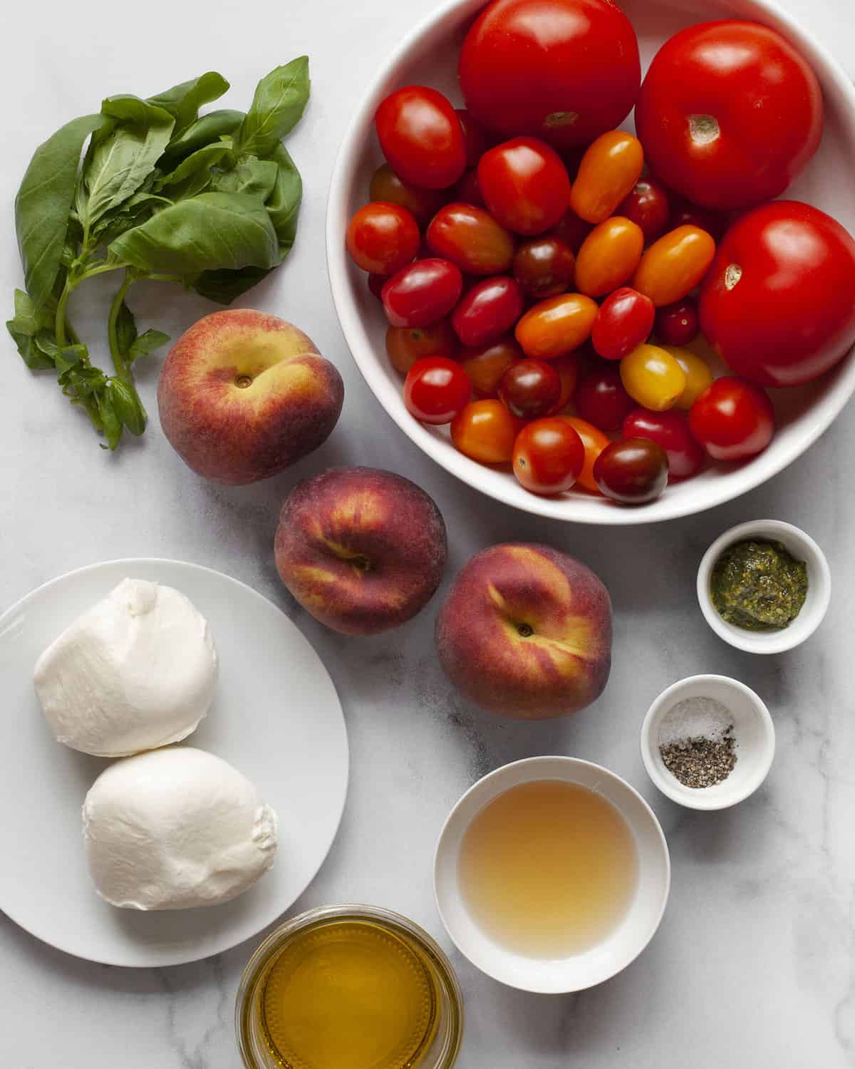 Ingredients including tomatoes, peaches, mozzarella, basil, olive oil, vinegar, pesto, salt and pepper.