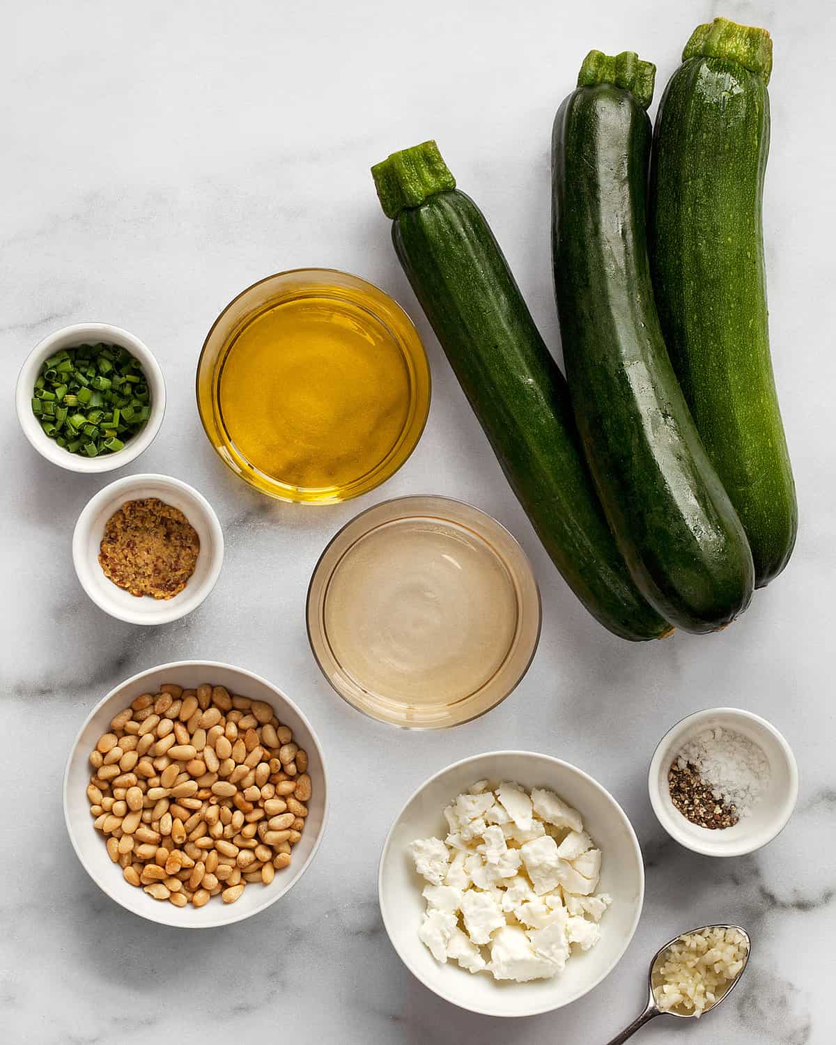 Ingredients including zucchini, feta, pine nuts, olive oil, white wine vinegar and herbs.