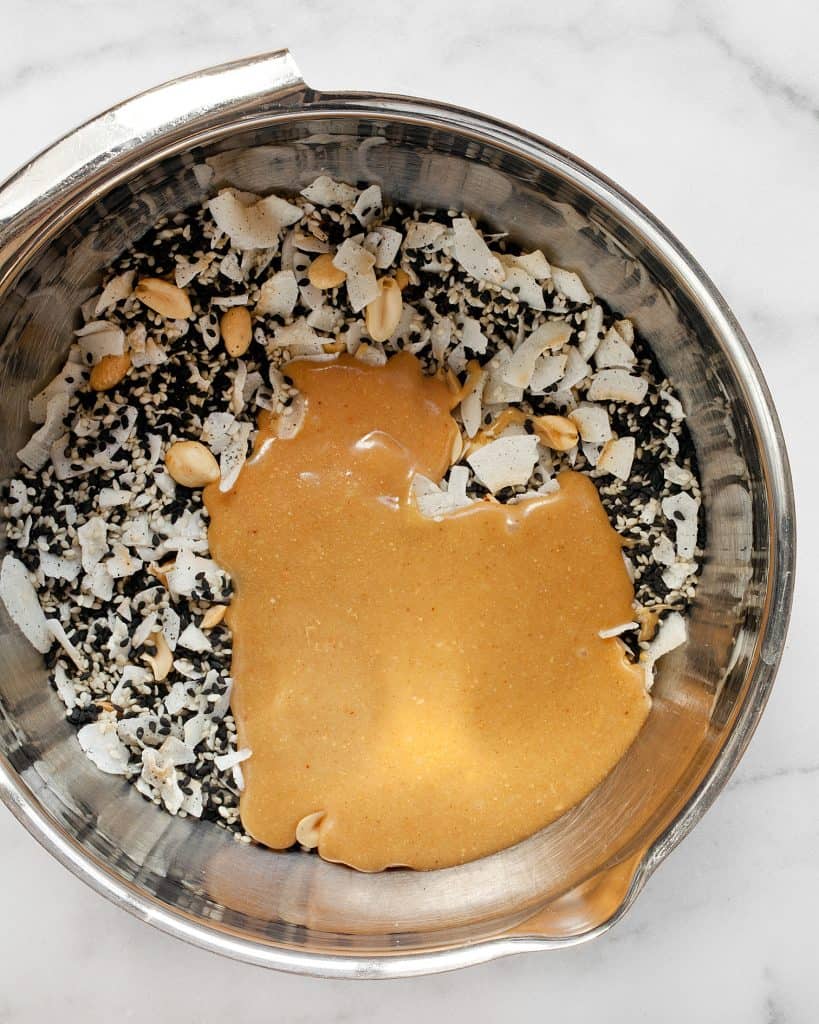 Stir the peanut butter mixture into the sesame seeds, peanuts and coconut flakes