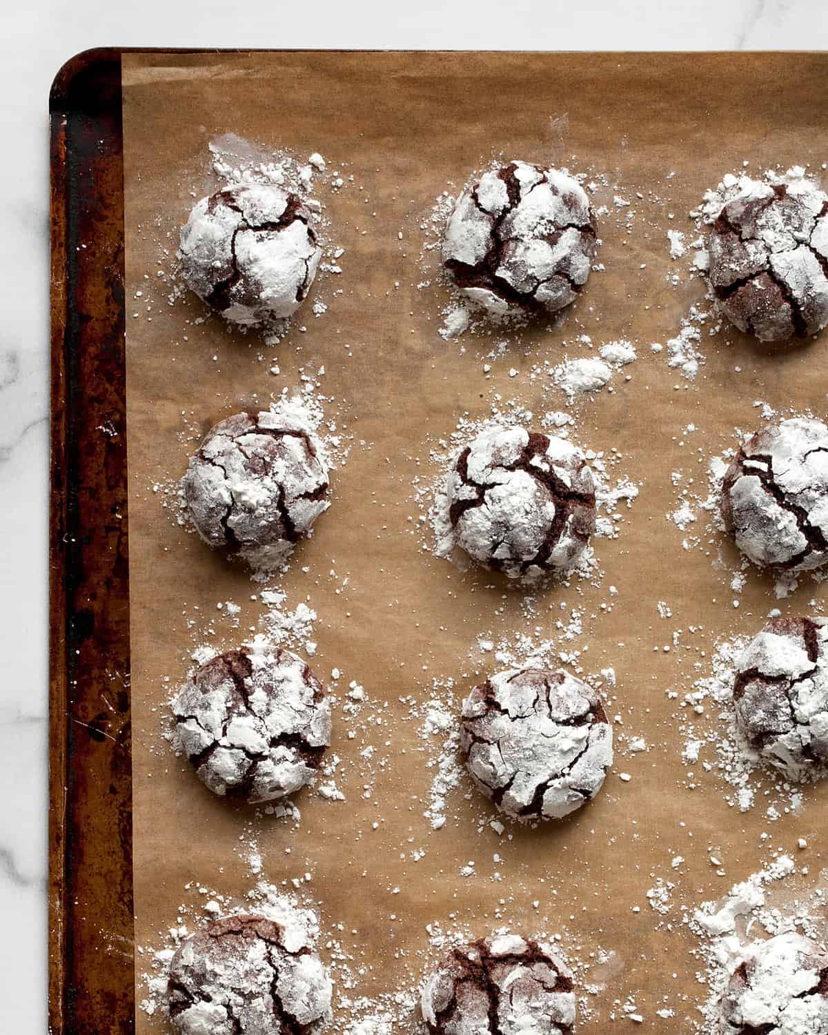 Baked crinkle cookies on a sheet pan.