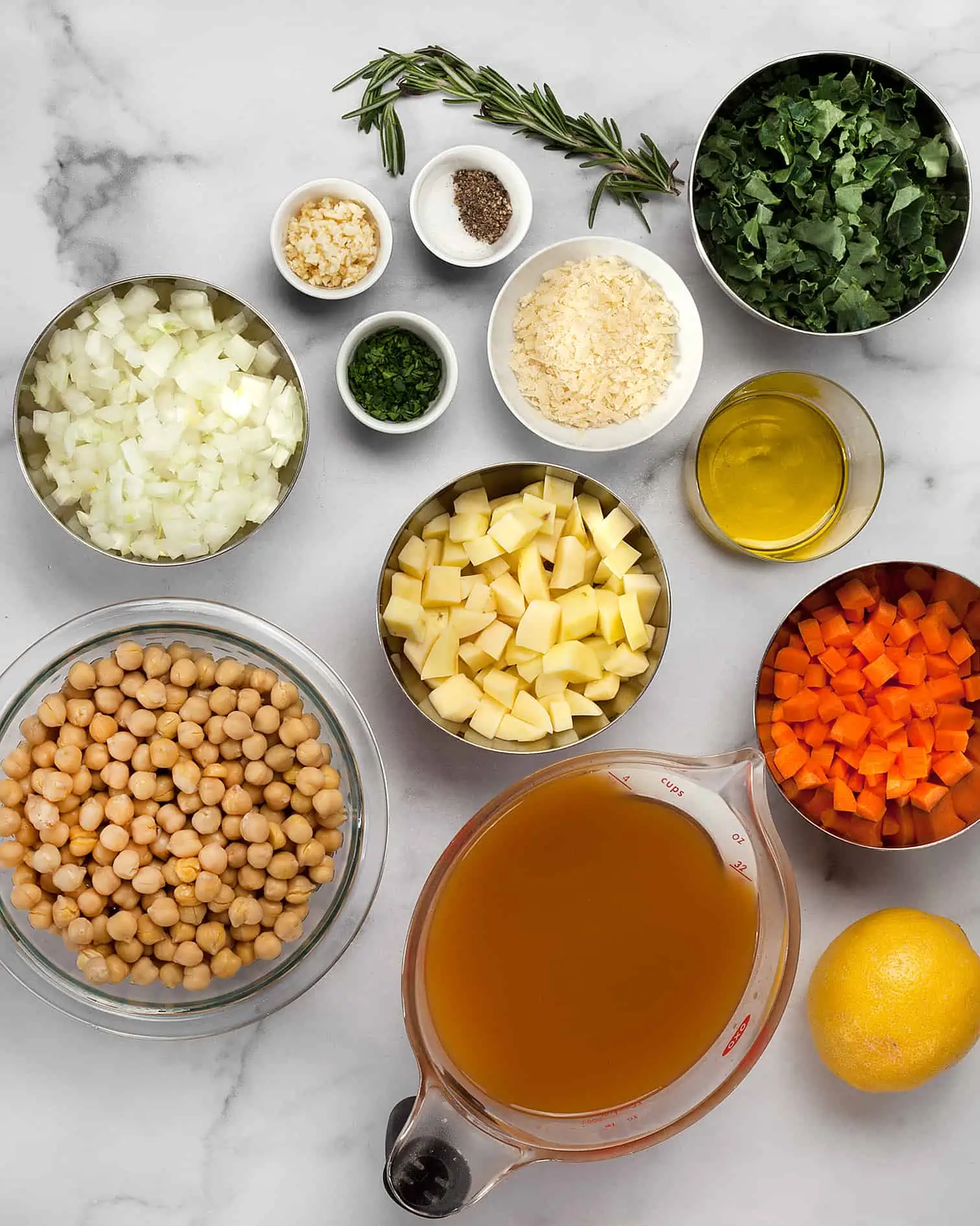 Ingredients including chickpeas, carrots, potatoes, kale, vegetable broth, onions, garlic and rosemary.