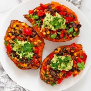 Three southwestern baked sweet potatoes on a plate.