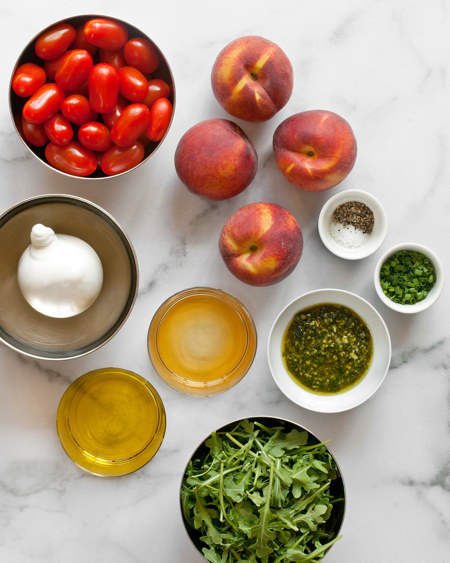 Ingredients including peaches, tomatoes, burrata, arugula and chives.