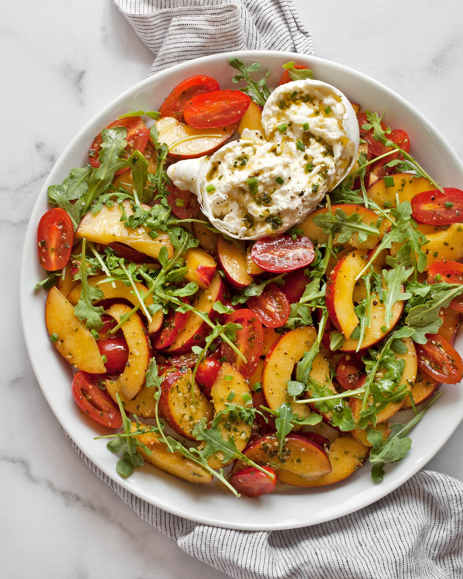 Tomato peach burrata salad on a plate.