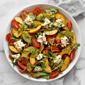 Tomato peach burrata salad on a plate.