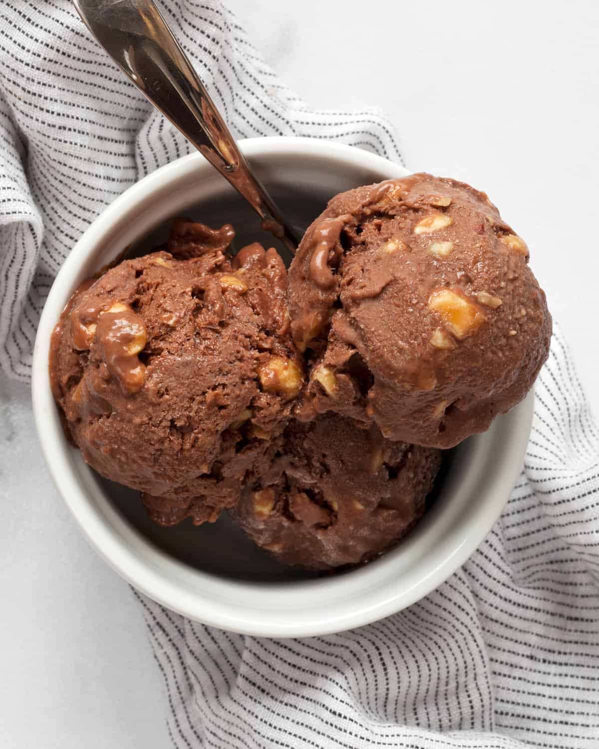 Vegan chocolate ice cream in a bowl with a spoon.