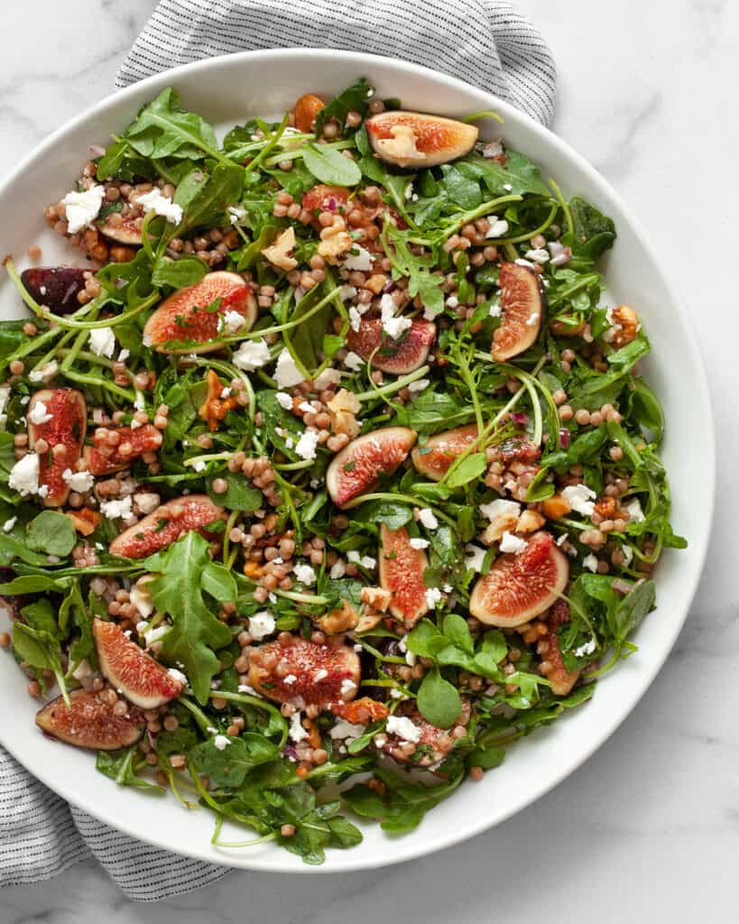 Fresh fig salad with arugula and couscous on a plate.