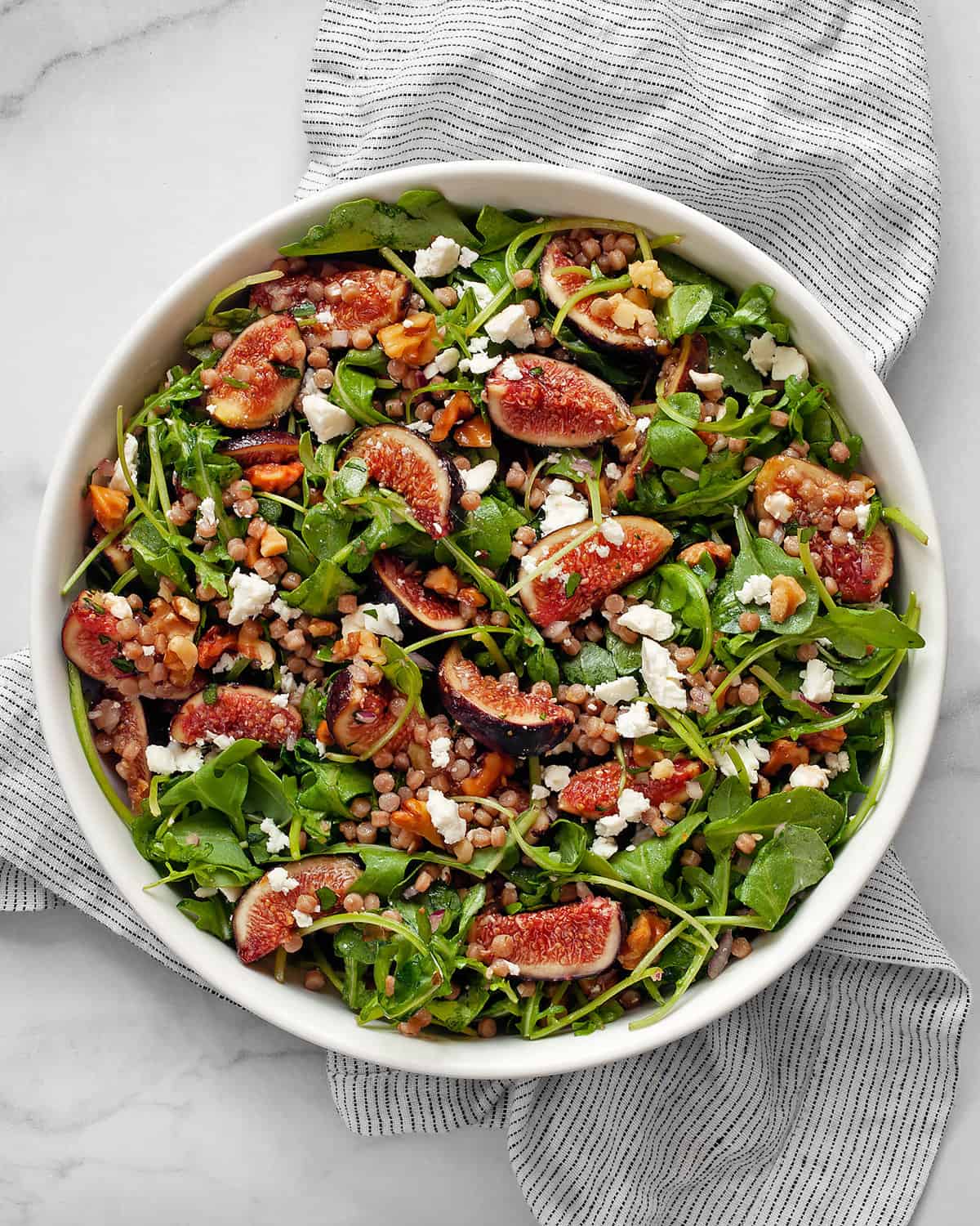 Fresh fig salad with arugula and couscous in a bowl.