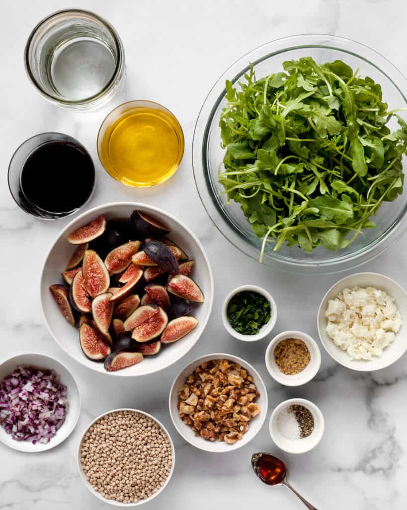 Ingredients including figs, arugula, walnuts, couscous, goat cheese, balsamic vinegar and olive oil.