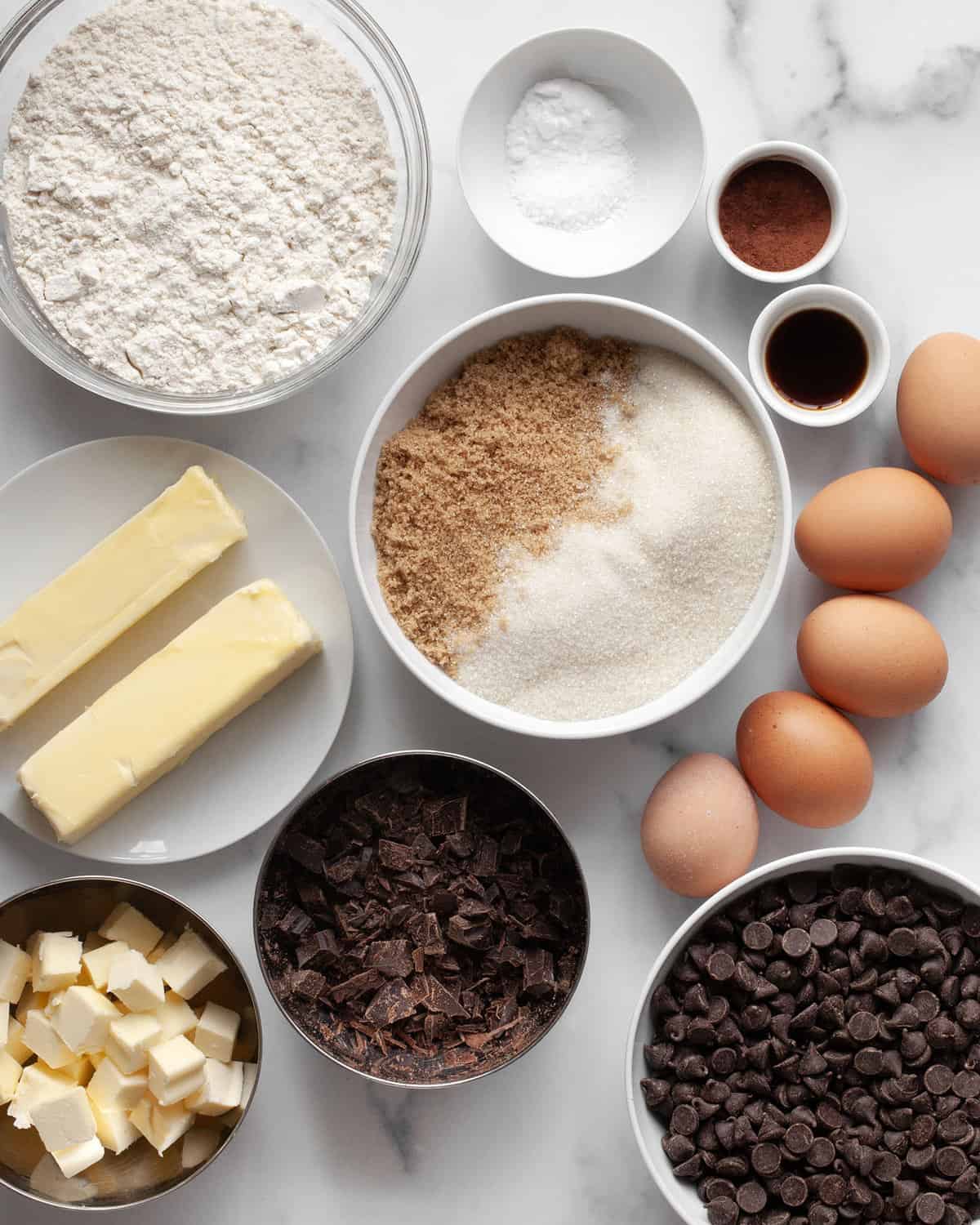 Ingredients including flour, salt, baking soda, butter, brown sugar, granulated sugar, eggs, vanilla extract and chocolate chips, cocoa powder and bittersweet chocolate