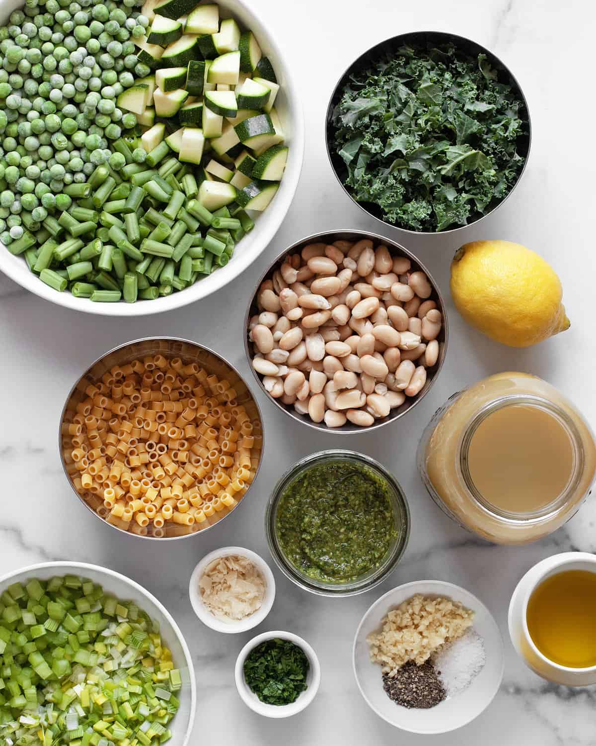 Ingredients including leeks, celery, green beans, zucchini, peas, kale, white beans, broth and olive oil.
