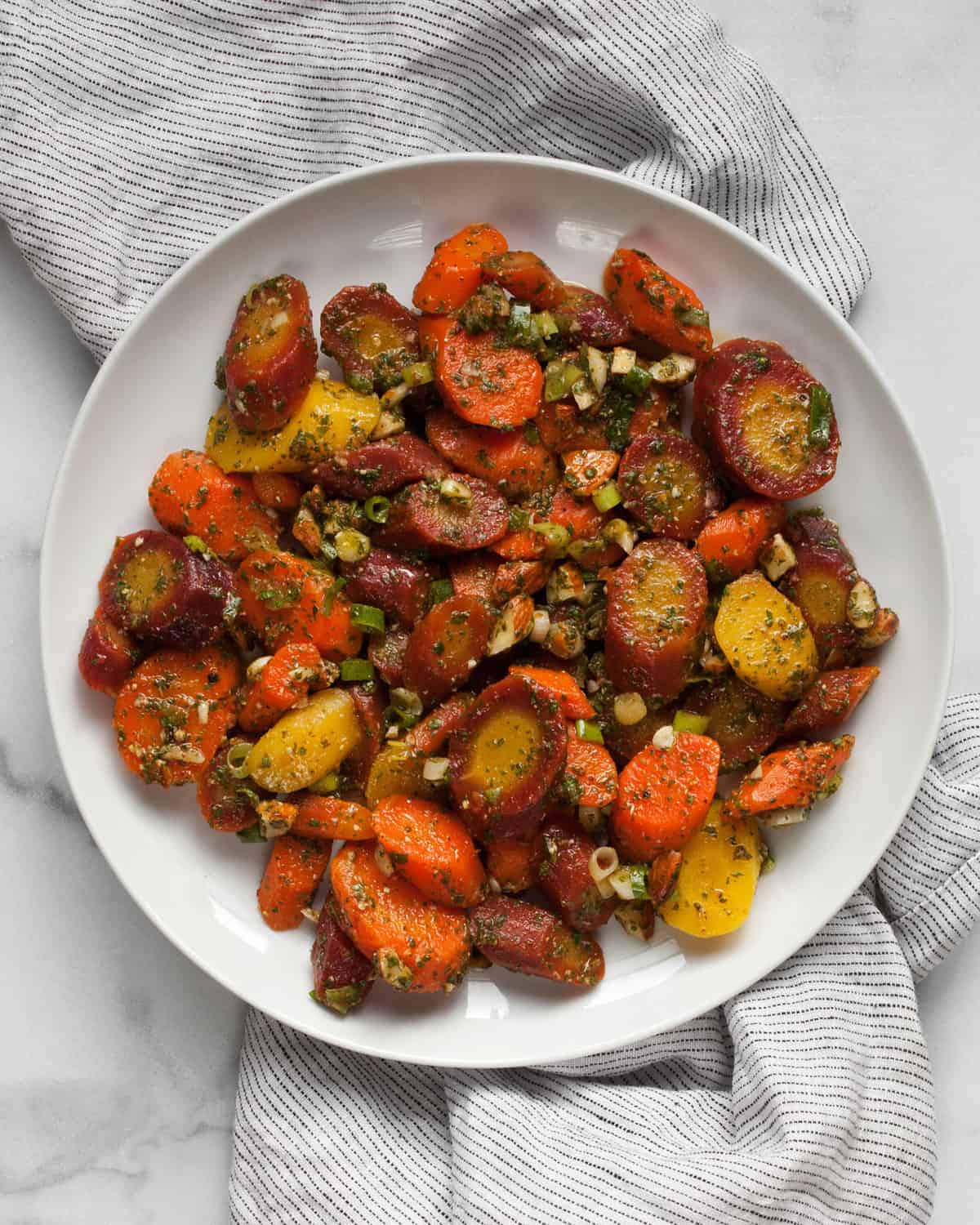 Carrot salad with scallions, almonds and herby dressing on a plate.