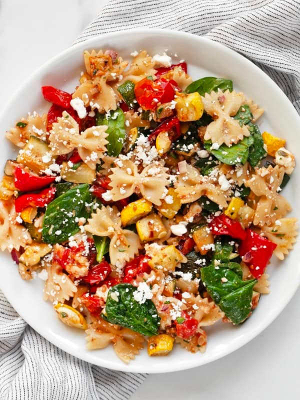 Roasted vegetable bow tie pasta salad on a plate.