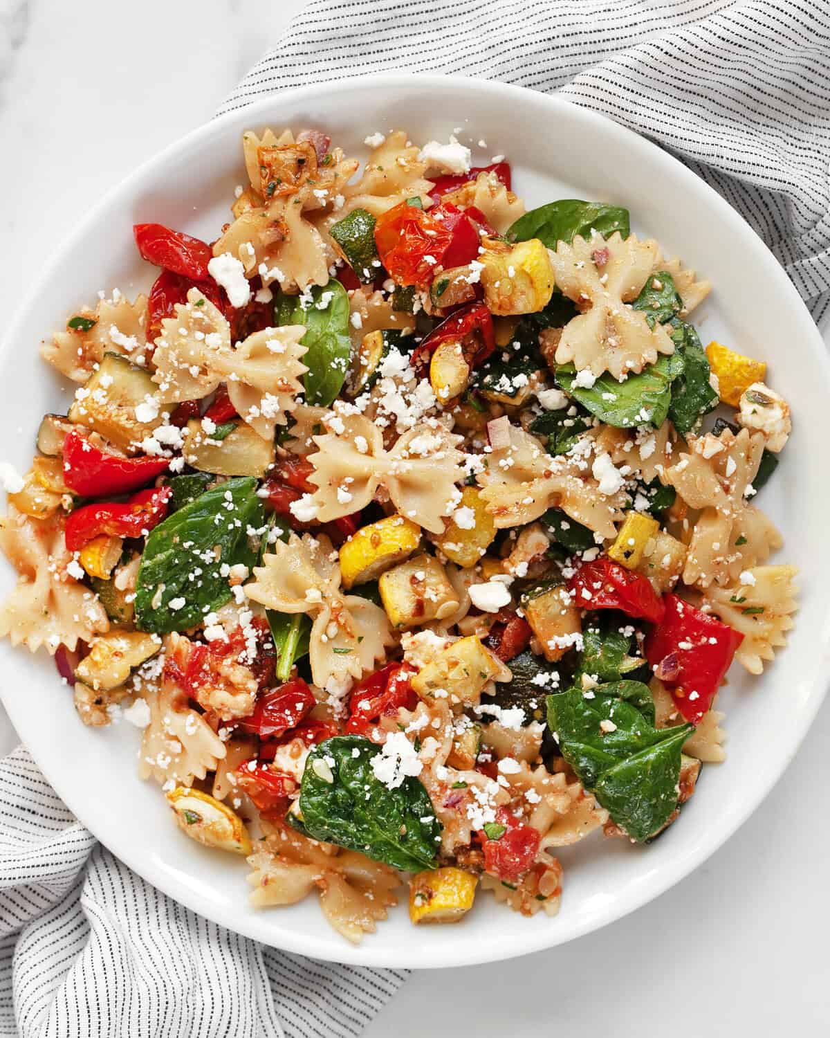 Roasted vegetable bow tie pasta salad on a plate.